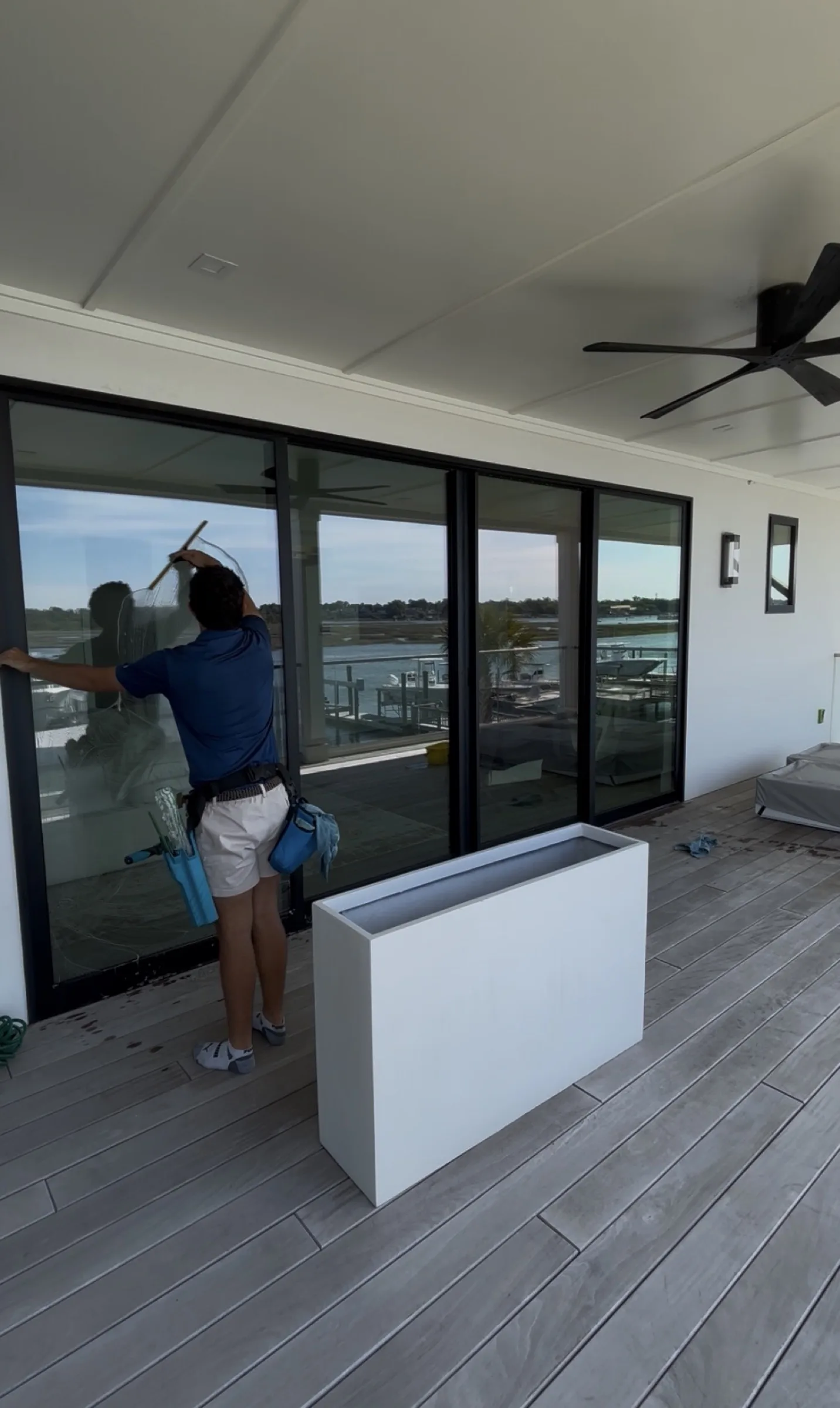 Cpt. Jack’s squeegee-finishing floor-to-ceiling sliding glass doors on a patio overlooking a marina